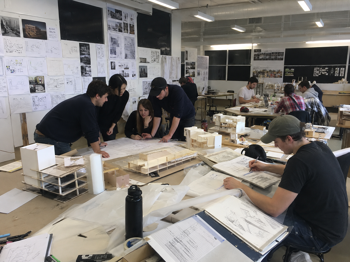 Architecture students and tutors reviewing models and drawings in studio